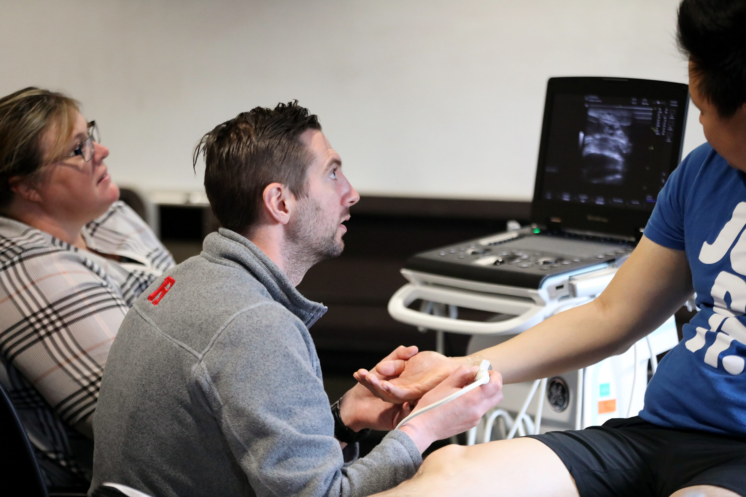 Medical resident sits with an instructor in front of a portable ultrasound machine.