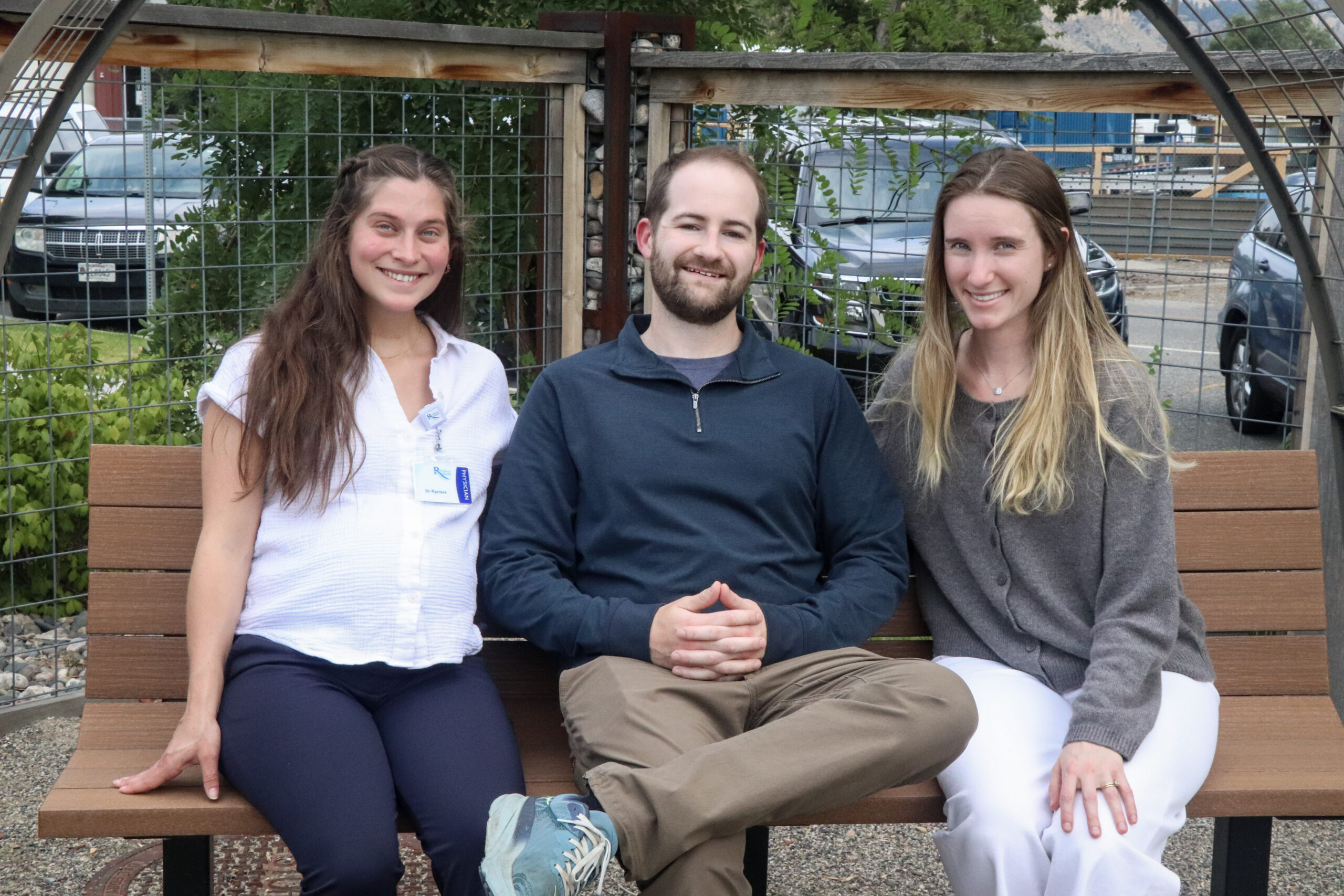 MFMR leads Sarah Ryersee and Lucas Teynor sitting on a wooden bench outside with Maddie Du Pont.